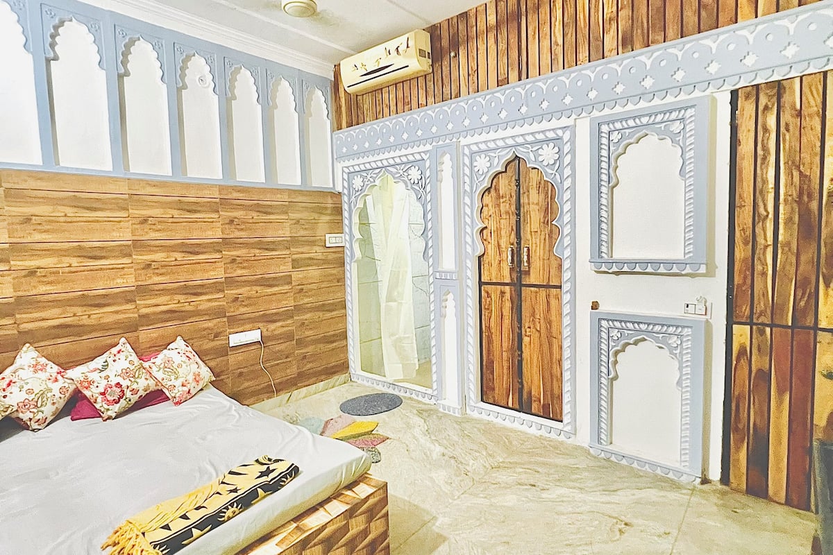 A bedroom with a bed, a ceiling fan, and a decorative wall panel.