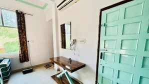 A bathroom with a wooden vanity, a mirror, a green door, and a window with curtains. - Bhoora House (Amer)