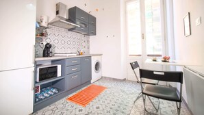 A compact kitchen with a washing machine, a microwave, and a coffee maker. - LIVE YOUR STAY (Genova)