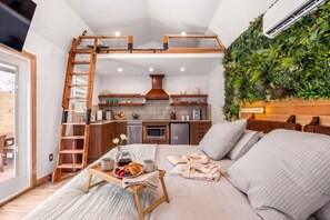 A cozy room with a loft bed, a dining area with breakfast, and a kitchen with modern appliances. - Romantic Luxury Retreat-hot/cold pool & sauna (Wimberley)