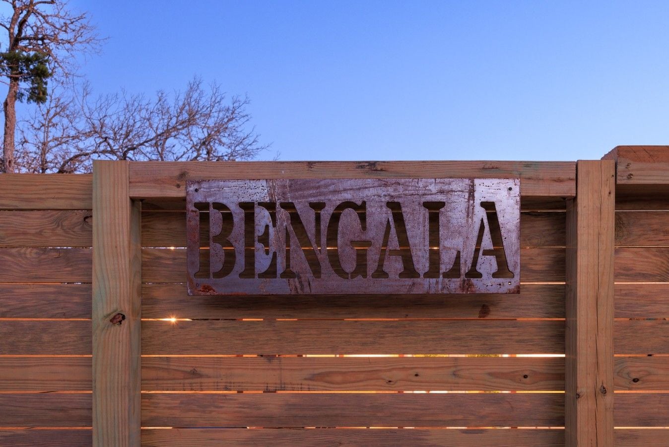 Een houten hek met een metalen bord waarop 'BENGALA' staat.