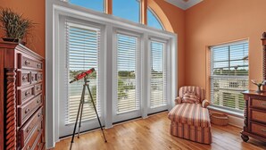 A room with large windows, a telescope, a striped armchair, and wooden furniture. - 🏖️🏝️Waterfront-Inlet Beach-Pool & Hot Tub-Red Retreat (Pensacola)