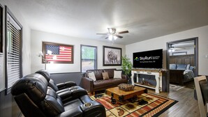 A living room with a brown leather sofa, a wooden coffee table, and a television displaying 'SkyRun Vacation Rentals'.
