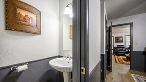 A bathroom with a white sink, a mirror, and a framed picture on the wall.