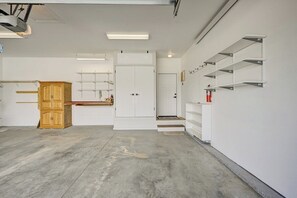 Una habitación amplia con piso de concreto, paredes blancas, un gabinete de madera y estanterías integradas.