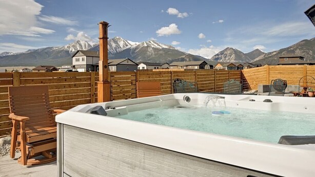 A hot tub with a wooden deck, a chair, and a mountain backdrop. - Mountain Haven Retreat w/Hot Tub & Sauna STR-283 (Buena Vista)