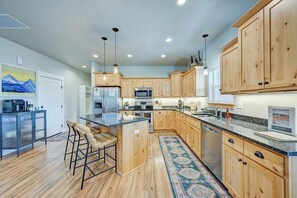 A modern kitchen with wooden cabinets, a central island, bar stools, and stainless steel appliances. - Mountain Haven Retreat w/Hot Tub & Sauna STR-283 (Buena Vista)