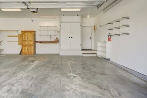 A spacious garage with a concrete floor, a wooden cabinet, a white door, and a fire extinguisher on the wall. - Mountain Haven Retreat w/Hot Tub & Sauna STR-283 (Buena Vista)