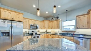 A modern kitchen with granite countertops, stainless steel appliances, wooden cabinets, and pendant lighting. - Mountain Haven Retreat w/Hot Tub & Sauna STR-283 (Buena Vista)