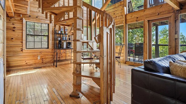 Ein Holzinterieur mit einer Wendeltreppe, einer Couch und großen Fenstern.