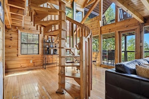 A wooden interior with a spiral staircase, a sofa, and large windows.