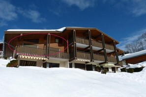 Ein mehrstöckiges Gebäude mit Balkonen, umgeben von Schnee.