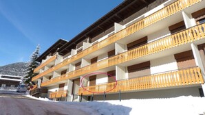 Un hôtel à plusieurs étages, doté de balcons en bois et dont le sol est recouvert de neige.
