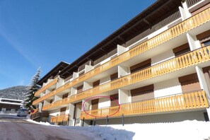 Um hotel com vários andares, varandas de madeira e o chão coberto de neve.