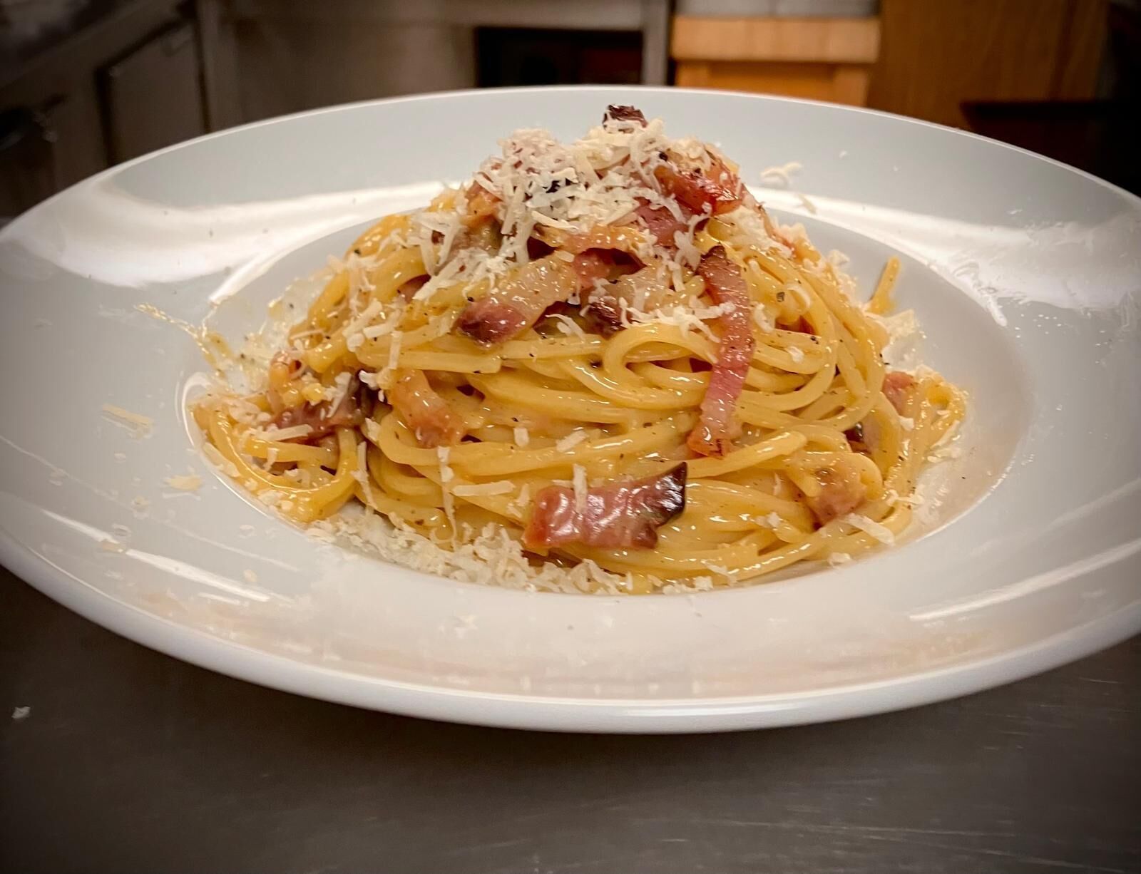 Un plato de espagueti con queso y tocino.
