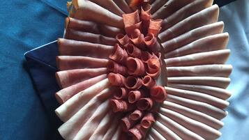 A plate of sliced meats and vegetables arranged in a circular pattern on a blue tablecloth.