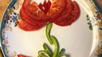 Ein Teller mit floralem Muster und Tomatenscheiben, die eine Blume bilden.