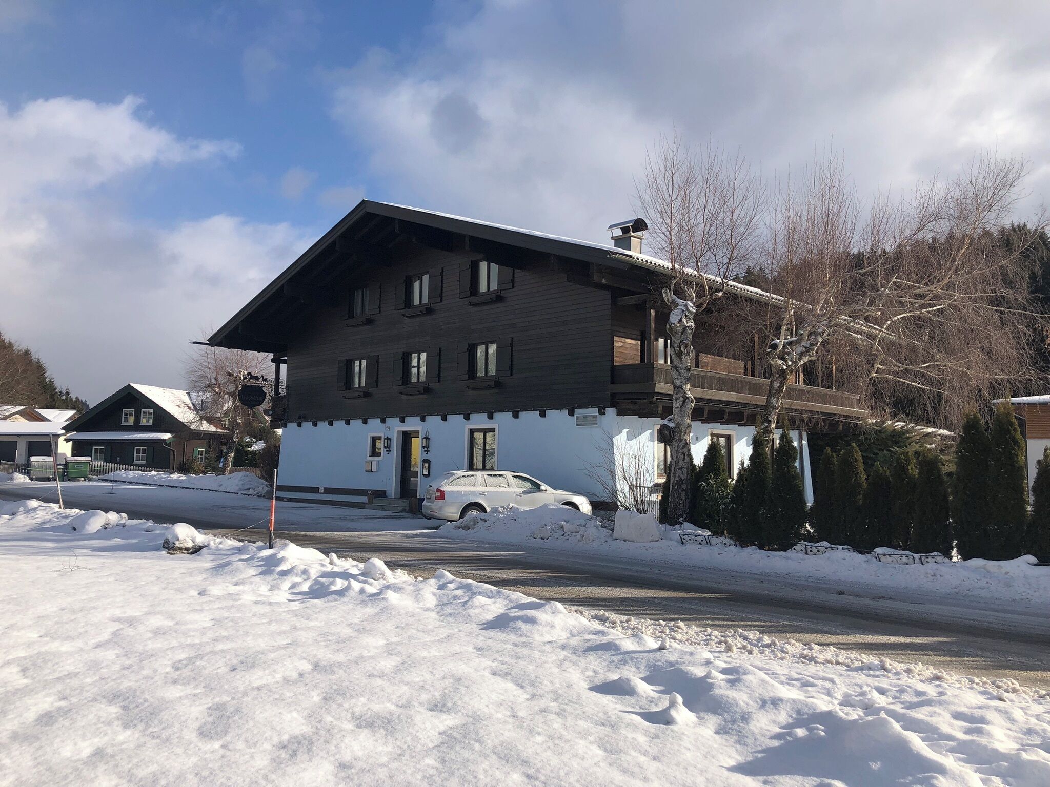 A two-story building with a sloped roof, a garage, and a snow-covered driveway.