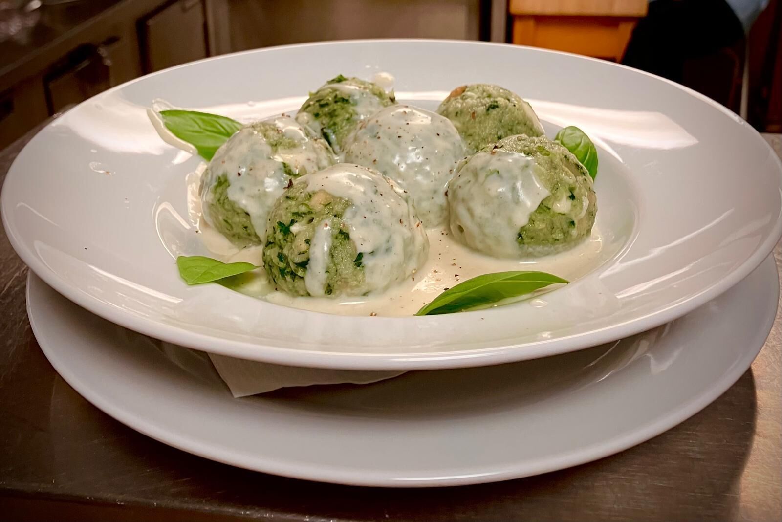 A plate of meatballs in a creamy sauce, garnished with basil leaves.
