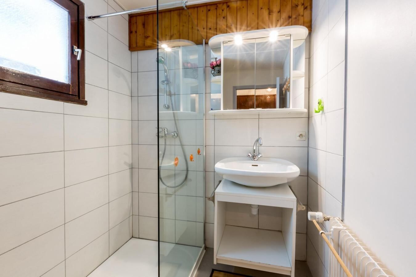 A modern bathroom with a glass-enclosed shower, a white sink, and a wooden ceiling.