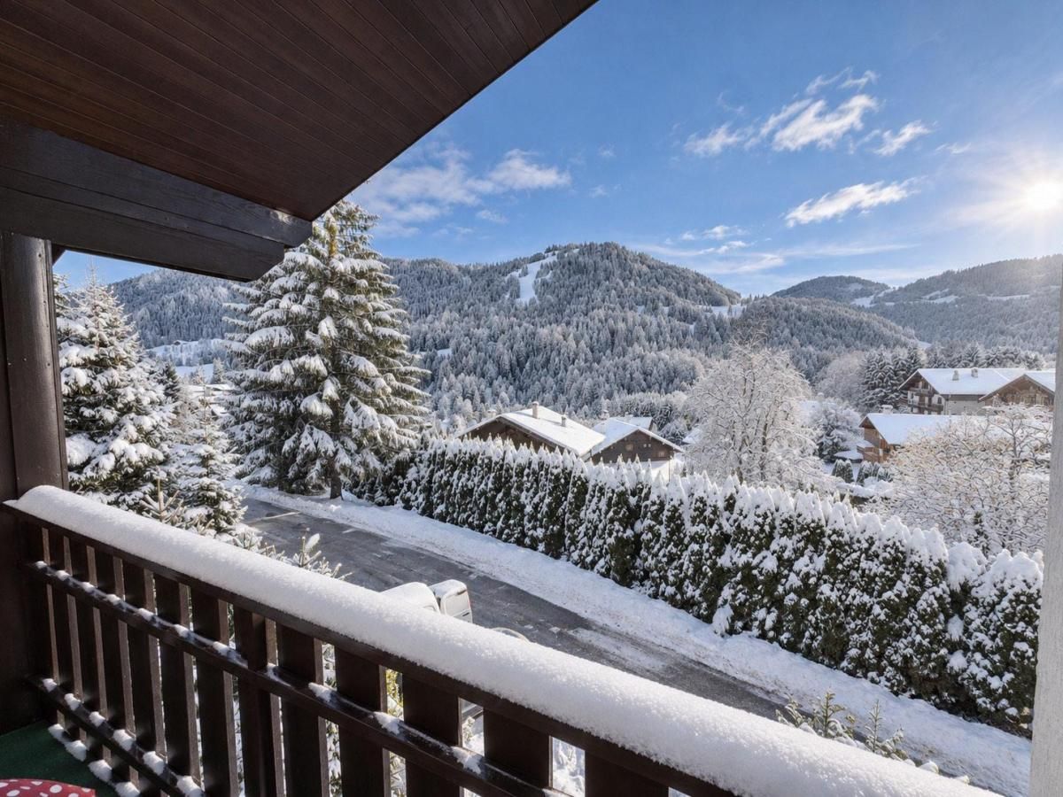 A balcony with a view of a snow-covered landscape, including trees and houses.