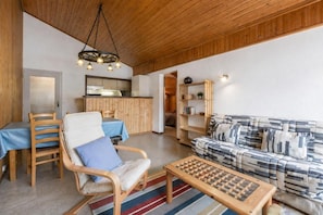 Ein gemütliches Wohnzimmer mit einer Couch, einem Holztisch, einem Sessel und einem Essbereich mit Tisch und Stühlen.