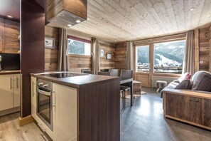 Una cocina moderna con una isla central, paredes de madera y ventanas amplias que ofrecen vistas a la montaña.