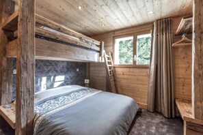 Un dormitorio de cabaña de madera con literas, una ventana con cortinas y una escalera.