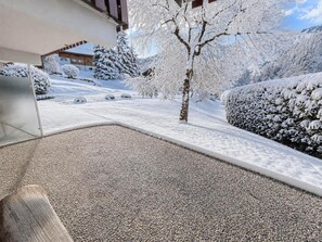 A snow-covered outdoor area with a gravel path leading to a building entrance.