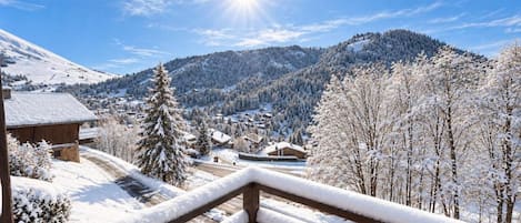 A snowy mountain landscape with a wooden balcony railing.