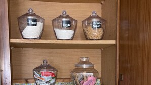 A kitchen cabinet with labeled containers for flour, sugar, and brown sugar, a spice rack, and a utensil holder. - Grant City Nightly Rental

 (Grant City)