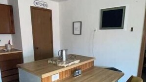 A compact kitchen with a wooden island, two yellow chairs, and a small window. - Grant City Nightly Rental

 (Grant City)