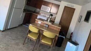A compact kitchen with a dining table and chairs, a refrigerator, and a microwave. - Grant City Nightly Rental

 (Grant City)