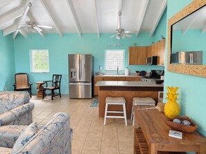 A compact kitchen with a central island, a refrigerator, and a dining area with a chair and table. - Shore Blessed! 2 bedroom, 2 Bathroom villa with private pool! (Christiansted)