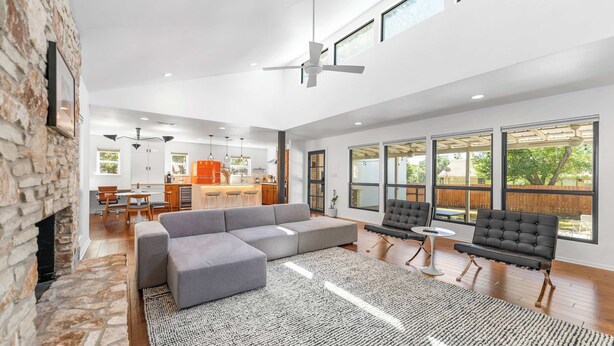 A spacious living area with a large sectional sofa, a fireplace, and a view of the backyard through large windows. - Close to Domain,DT,Shopping | Chic & Serene | 3BR (Austin)