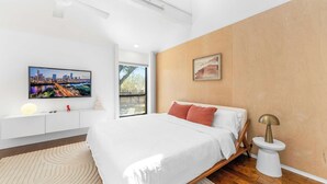 A modern bedroom with a bed, a TV, a painting, and a bedside lamp. - Close to Domain,DT,Shopping | Chic & Serene | 3BR (Austin)