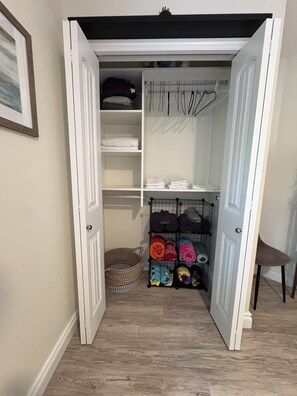 A walk-in closet with open doors, shelves, and a hanging rack.
