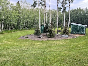 A well-maintained grassy area with a small cluster of trees and a green shed.