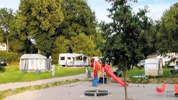 A playground with a red slide and a circular climbing structure. - 6 Person Holiday Home in Aabenraa (Aabenraa)