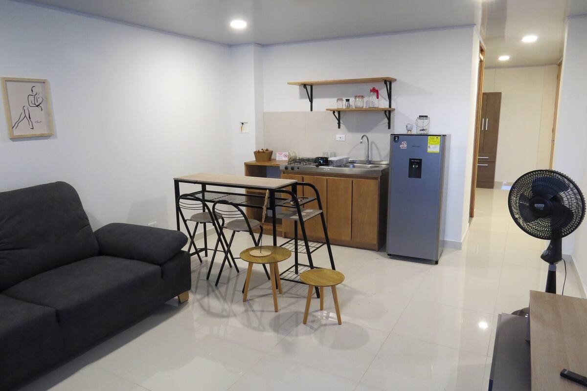 Un espace de vie compact comprenant un coin cuisine, un coin repas avec une table et des chaises, et un canapé.
