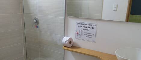 Une salle de bain moderne avec une douche à parois de verre, des toilettes, un lavabo avec un receveur et un miroir au-dessus du lavabo.