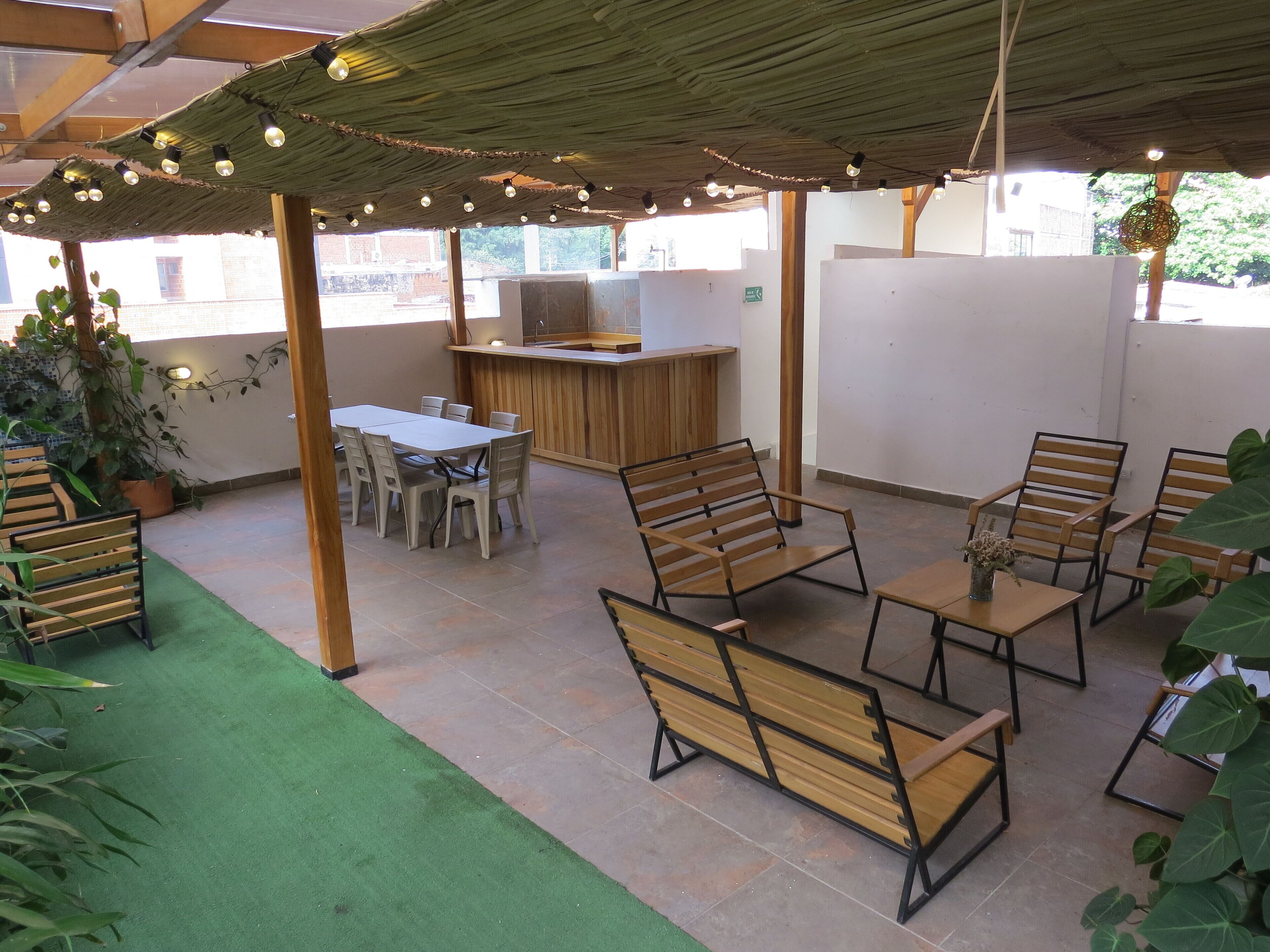 An outdoor patio with a wooden table and chairs, a wooden bench, and a green artificial turf area.