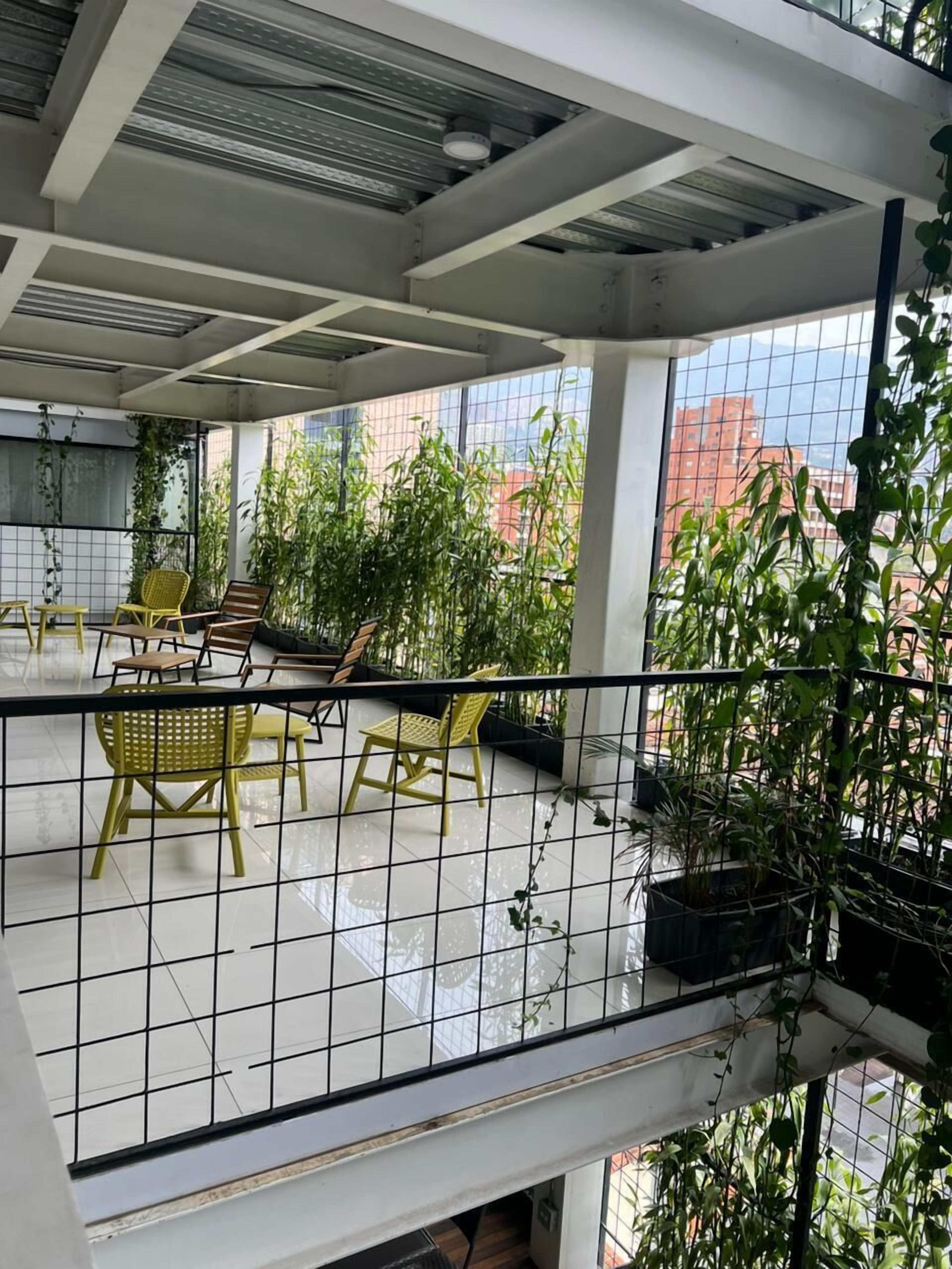 A balcony with yellow chairs and potted plants, overlooking a cityscape.
