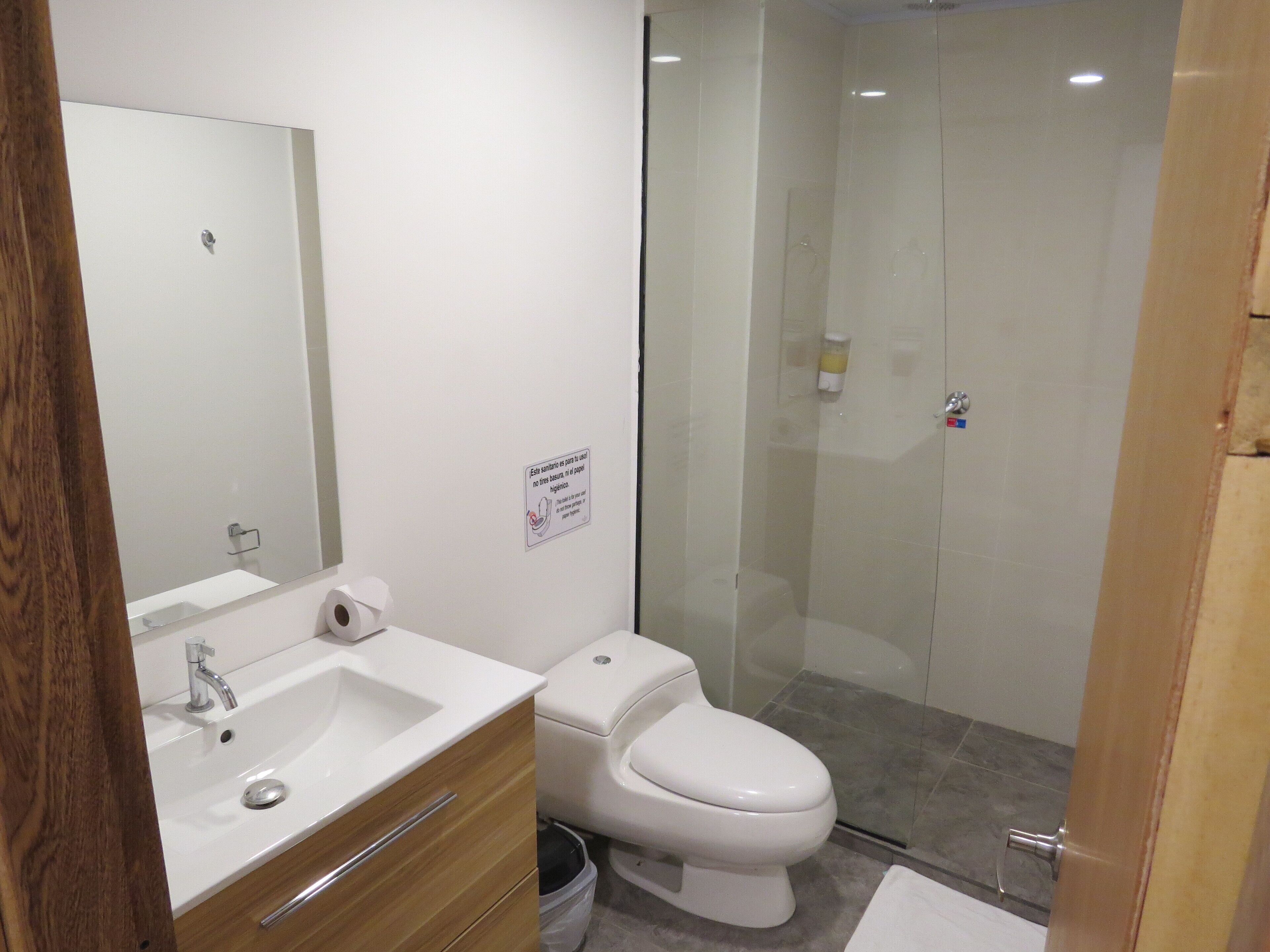 Ein modernes Badezimmer mit Waschbecken, Spiegel und Toilette in Weiß.