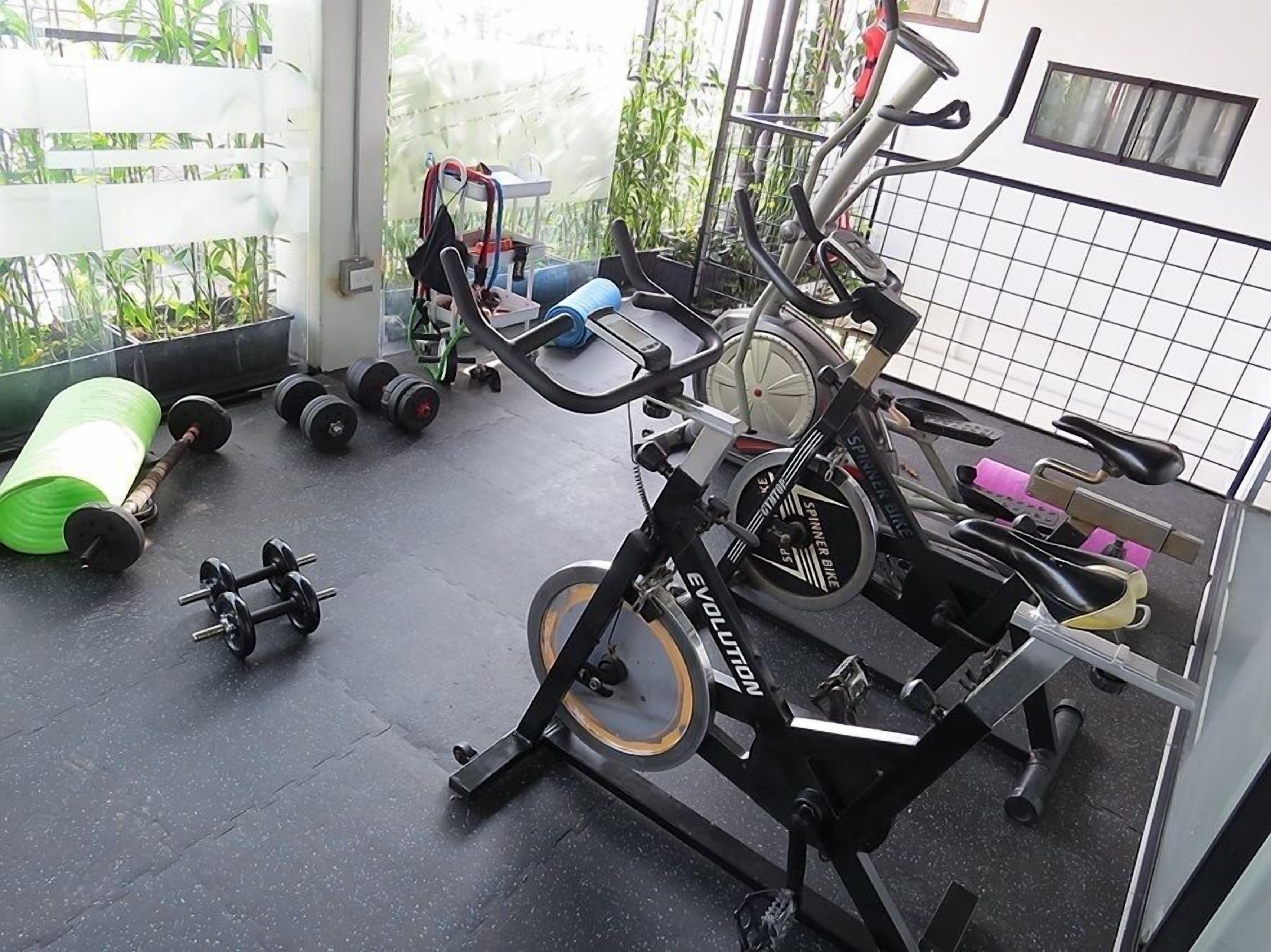 A home gym with a stationary bike, dumbbells, and a yoga mat.