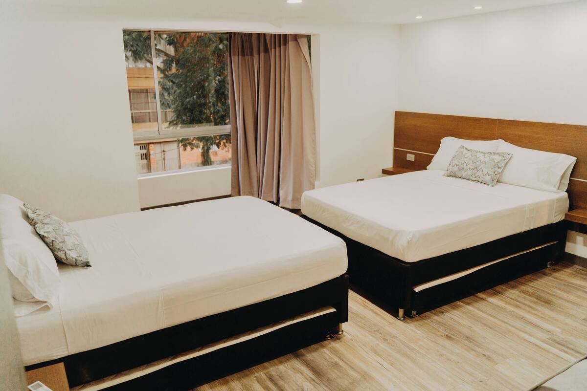 Une chambre d’hôtel avec deux lits, une fenêtre avec des rideaux et une vue sur l’extérieur.