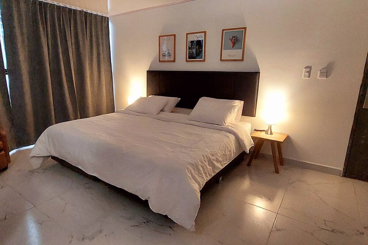 Une chambre d’hôtel avec un lit, une chaise, une table de chevet et une porte.