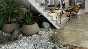 Un interior moderno con una escalera de caracol, suelo de madera y plantas en macetas.