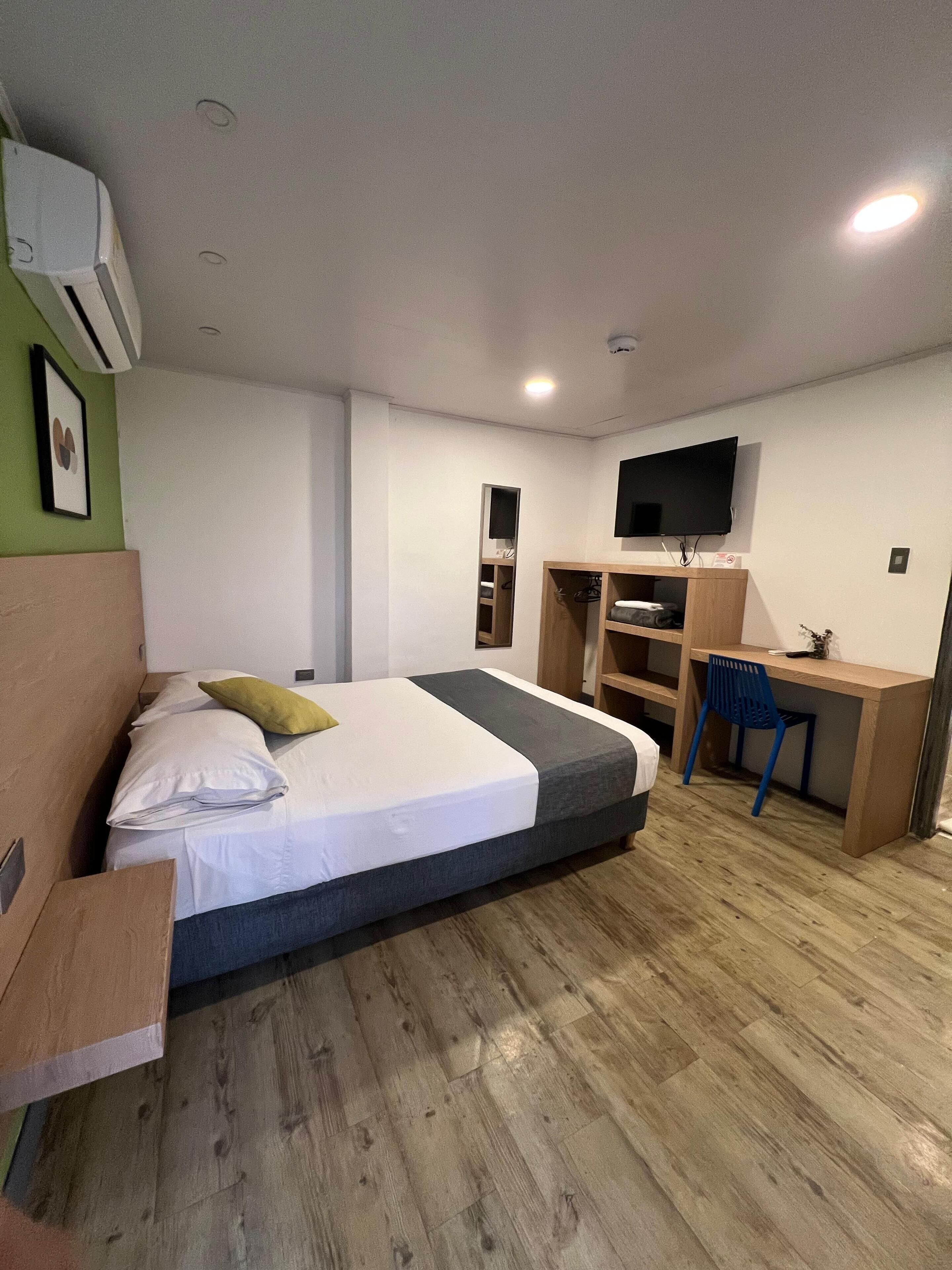 Ein modernes Hotelzimmer mit Bett, Schreibtisch, Fernseher und integrierten Regalen.