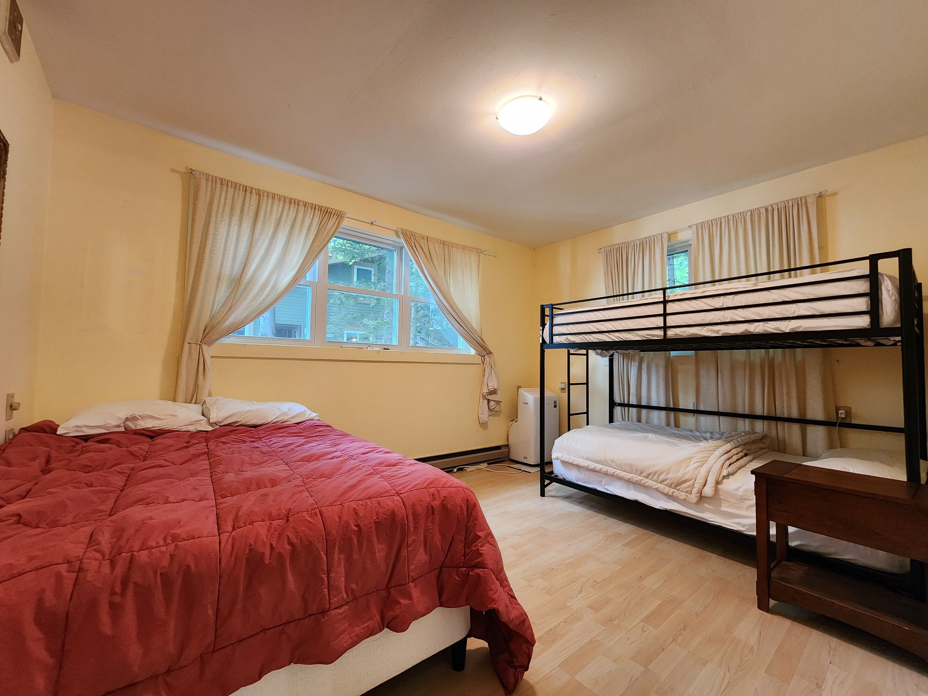 Un dormitorio con una cama litera, una cama individual y un banco de madera.